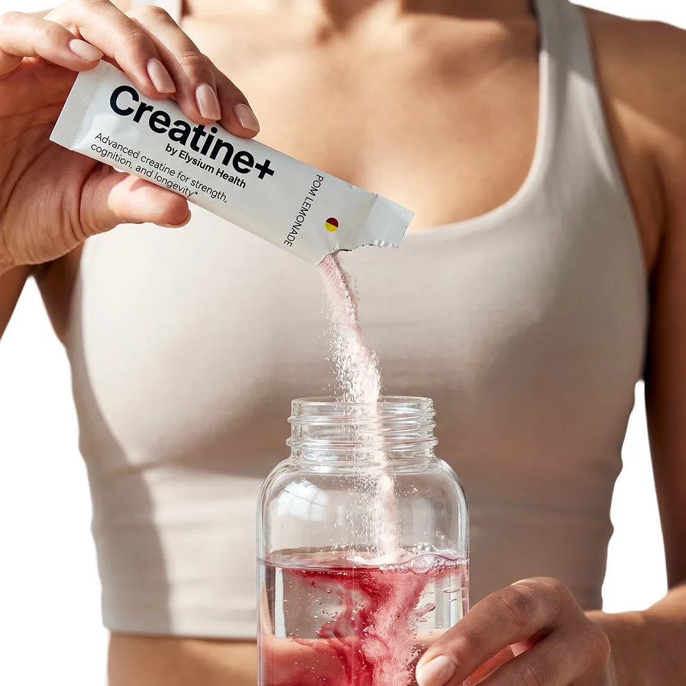 A woman pouring a Creatine+ stick into a bottle of water