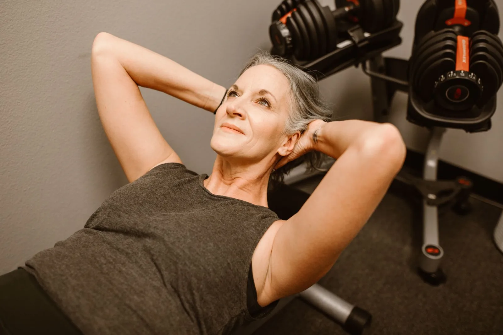 A strong woman over 50 training beside a rack of dumbbells